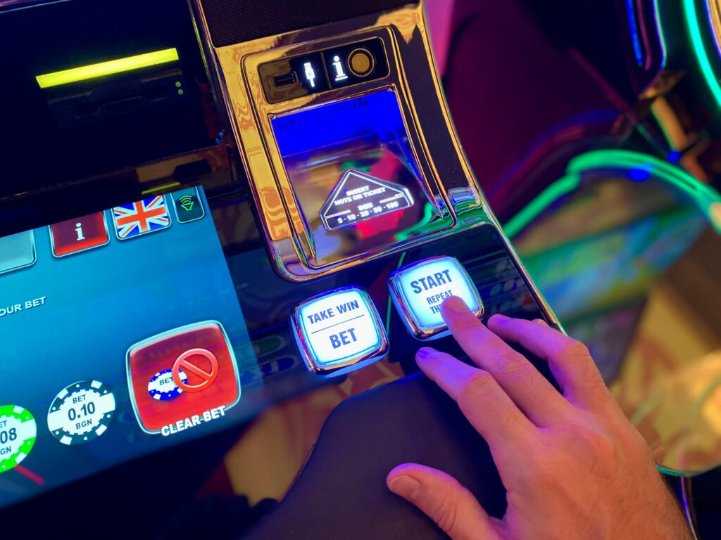 pexels-photo-30516010-30516010 Hand interacting with buttons on a colorful casino slot machine interface.